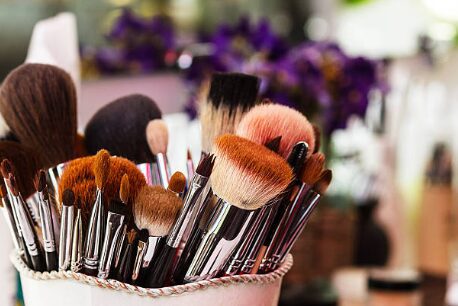 Makeup brushes in a holder, colorful background.